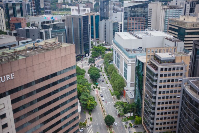 Aerial view of a bustling modern city streetscape with office buildings and greenery.