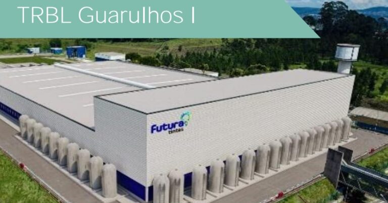 Galpão logístico moderno com caminhões nas docas durante o amanhecer, ilustrando propriedades do fundo imobiliário TRBL11.