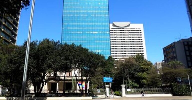 Edifício corporativo espelhado refletindo o céu, representando as lajes comerciais do fundo RCRB11.