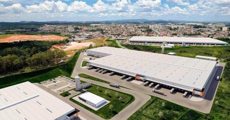 Caminhões de carga saindo de um moderno centro de distribuição logístico ao amanhecer, representando e-commerce.