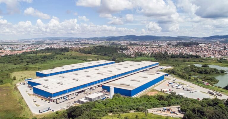 Fachada de um galpão logístico moderno com caminhões estacionados nas docas.