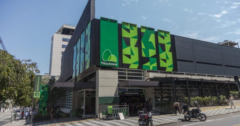 Fachada moderna de um grande supermercado comercial de esquina iluminado à noite
