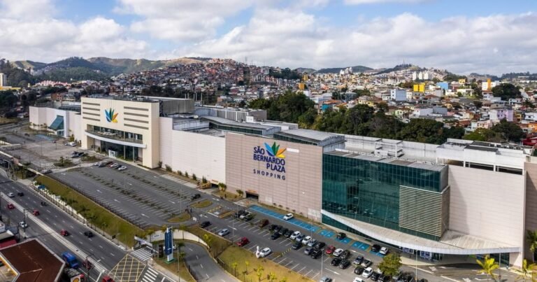 Fachada moderna de um shopping center movimentado ao anoitecer.
