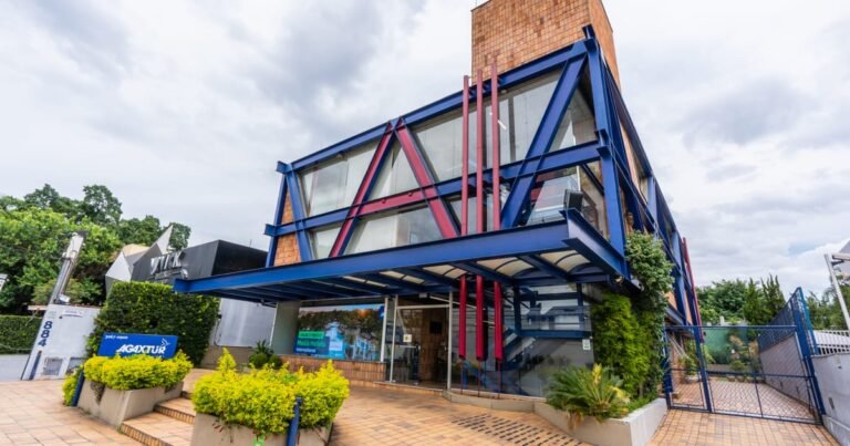 Fachada de prédio comercial moderno com três andares cercado por árvores, representando um ativo imobiliário de alto padrão.
