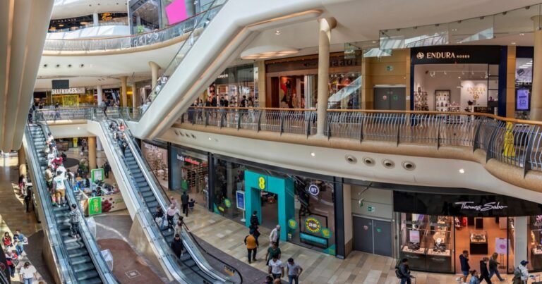 Fachada de um shopping center moderno iluminado ao anoitecer, representando o setor de fundos imobiliários de varejo