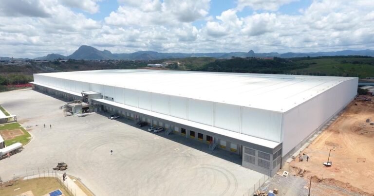 Vista aérea de um moderno condomínio logístico com carretas estacionadas no pátio.