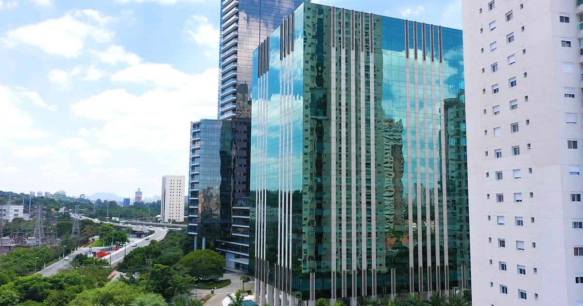 Fachada moderna de prédio comercial espelhado, representando as novas compras de escritórios do fundo TRXF11.