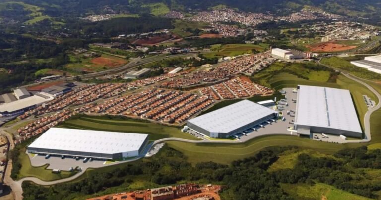 Fachada de galpão logístico moderno com docas e caminhões