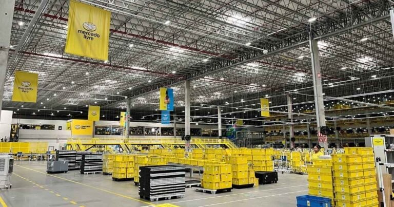 Galpão logístico moderno em construção com caminhões de carga no pátio.